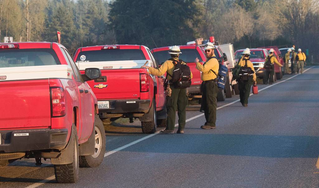 Trucks line Highway 9 as Department of Natural Resources firefighters head toward different areas of a brush fire Wednesday in Bryant. (Andy Bronson / The Herald)