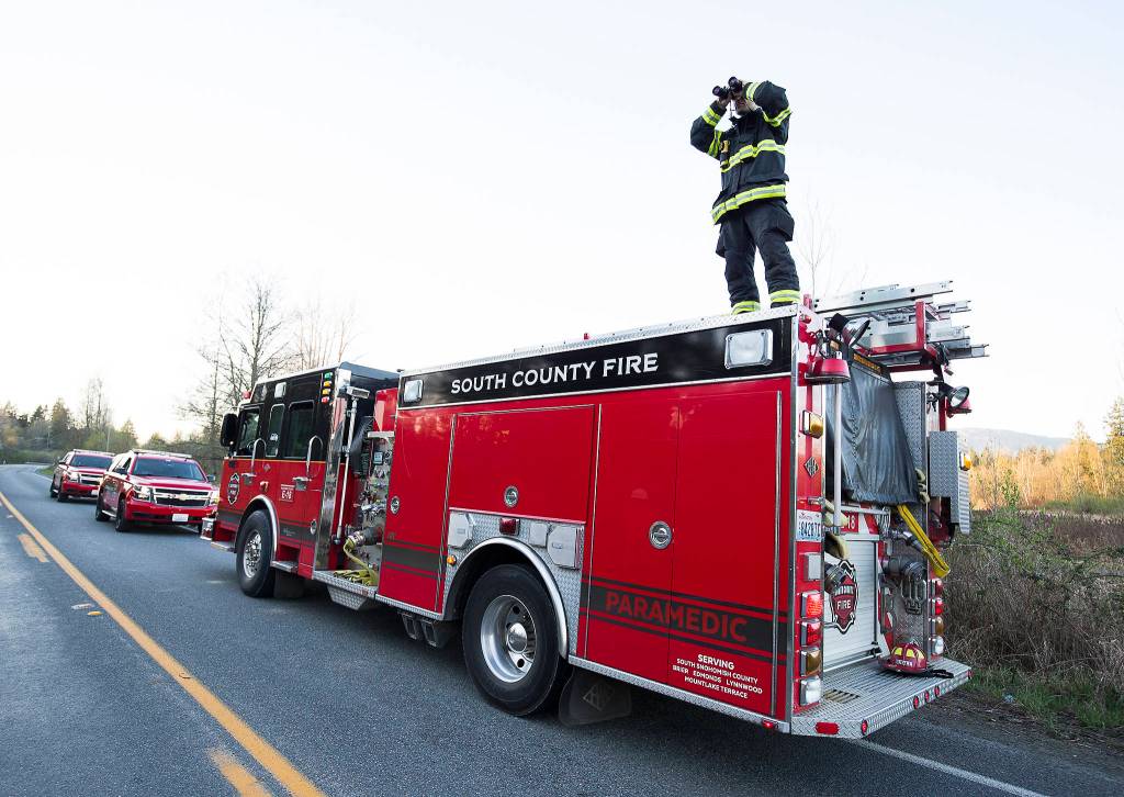 Jason Shield of South County Fire watches a fire as multiple strike teams from Snohomish County fire departments fight a large brush fire along Highway 9 on Wednesday in Bryant. (Andy Bronson / The Herald)
