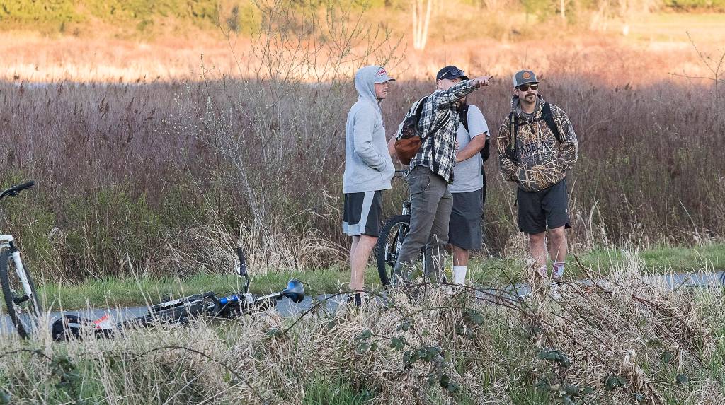 Bike riders watch from the Centennial Trail as multiple strike teams from Snohomish County fire departments fight a large brush fire along Highway 9 on Wednesday in Bryant. (Andy Bronson / The Herald)