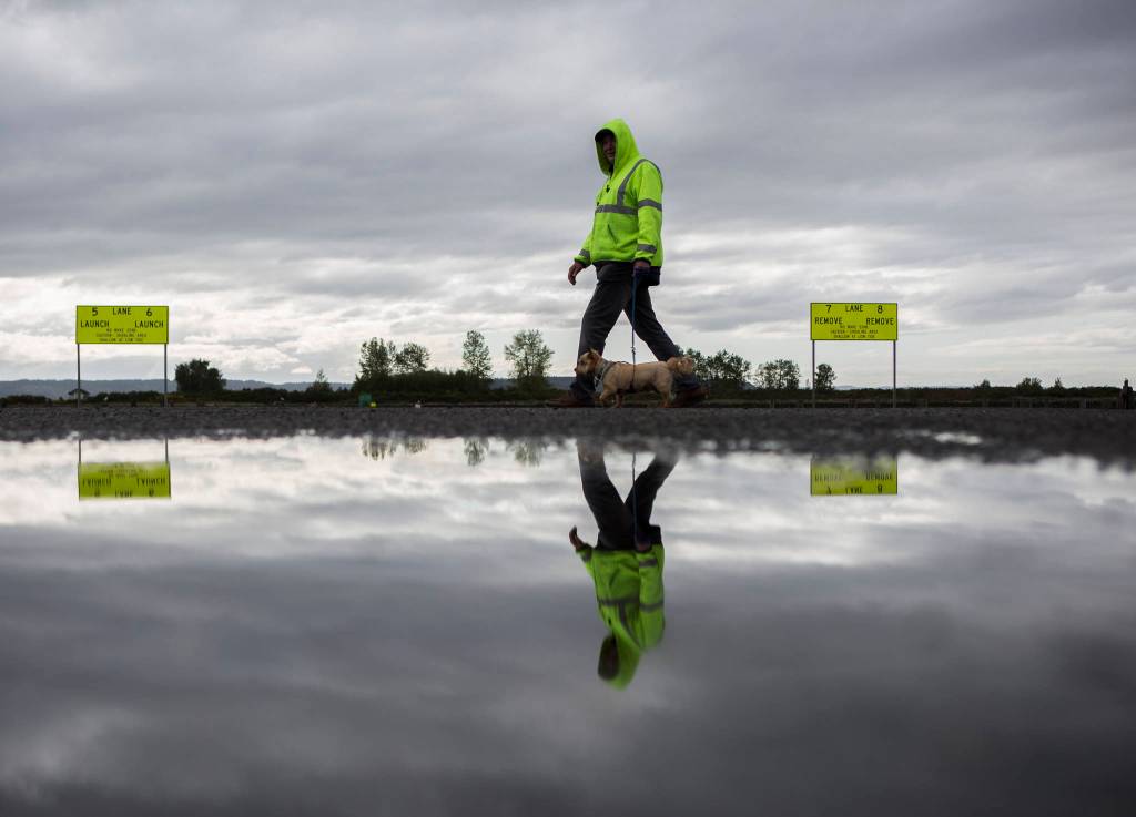 A man walks a dog past the 10th Street Boat Launch. (Olivia Vanni / The Herald)