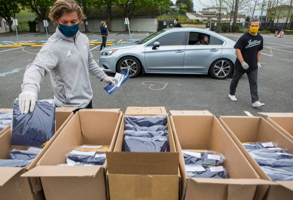 Jostens employees give Everett High School students their graduation gowns Tuesday in Everett. (Olivia Vanni / The Herald)