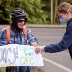 Annabelle Heiman (right) attaches a sign to Gary Lockes bike in preparation as guest of honor in a parade down 53rd Avenue West in Mukilteo. The block does a 2 minutes of gratitude nightly tribute to those on the frontlines. (Kevin Clark / The Herald)