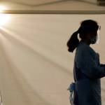 A nurse at a drive-up coronavirus testing station set up by the University of Washington Medical Center waits by a tent in Seattle in March. Between now and 2025, there will be a shortage of some 7,000 registered nurses in Washington state, according to a federal nursing worforce survey (Ted S. Warren / Associated Press file photo)