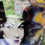 A woman is reflected in one of her older paintings as she works on a new painting at her home on Sunday in Everett. (Olivia Vanni / The Herald)