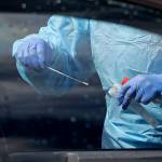 A medical assistant prepares to take a swab from a patient at a new drive-thru and walk-up coronavirus testing site April 25 in Seattle. (AP Photo/Elaine Thompson)