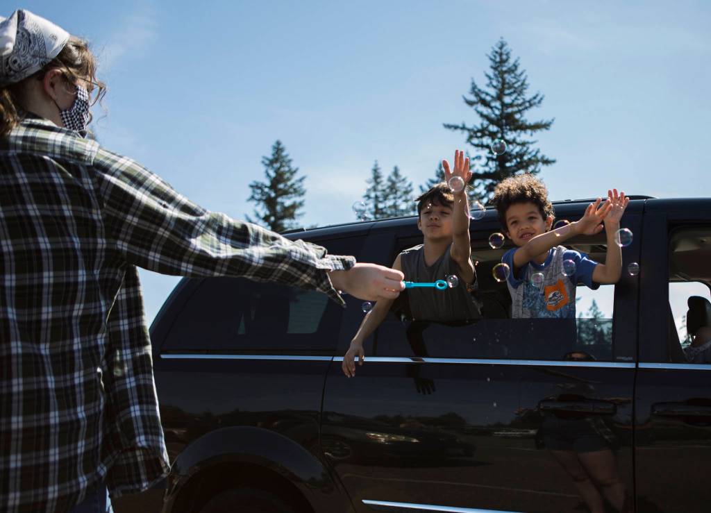 Owyn, 8 (left), and his brother Leon, 6 (right), play with bubbles from the car window while their mom tunes into the church service at the Marysville Foursquare Gospel Church on Sunday. (Olivia Vanni / The Herald)