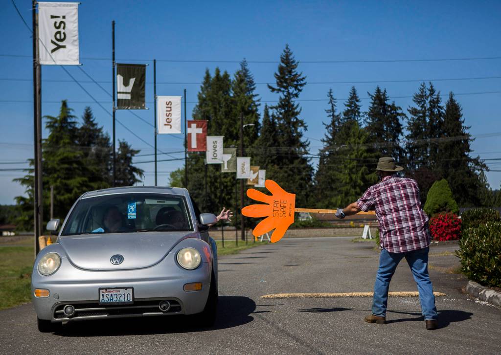 Olivia Vanni / The Herald                                Arthur Bender sticks out his sign to direct and high-five a drive-in churchgoer Sunday at Marysville Foursquare Gospel Church.