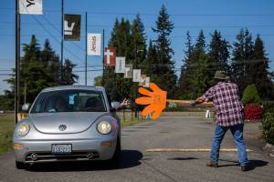 Arthur Bender, right, sticks out his sign to direct and high-five a drive-in church goer at Marysville Foursquare Gospel Church on Sunday, May 10, 2020 in Marysville, Wa. (Olivia Vanni / The Herald)