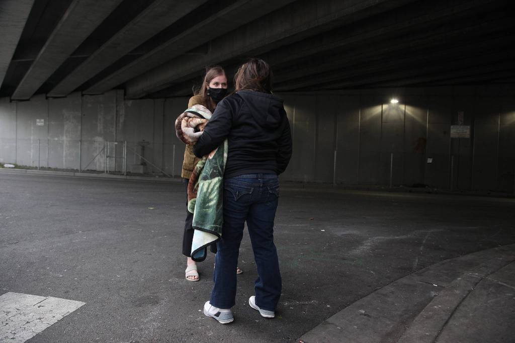 Angel Resource Connection volunteer Ana Faoro talks with a woman as she and other volunteers assist people with signing up for stimulus checks. (Andy Bronson / The Herald)