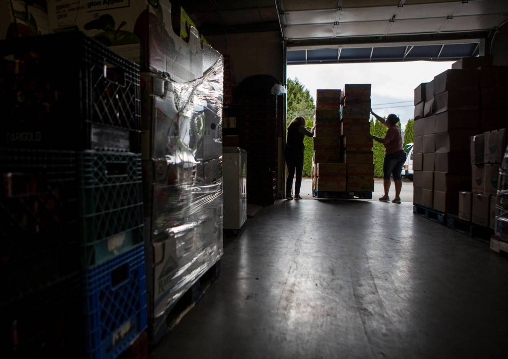 Cindy Chessie, left, and Becky Grannan help guide a pallet though the stacks of food at the Sky Valley Food Bank on Friday, May 15, 2020 in Monroe, Wa. (Olivia Vanni / The Herald)