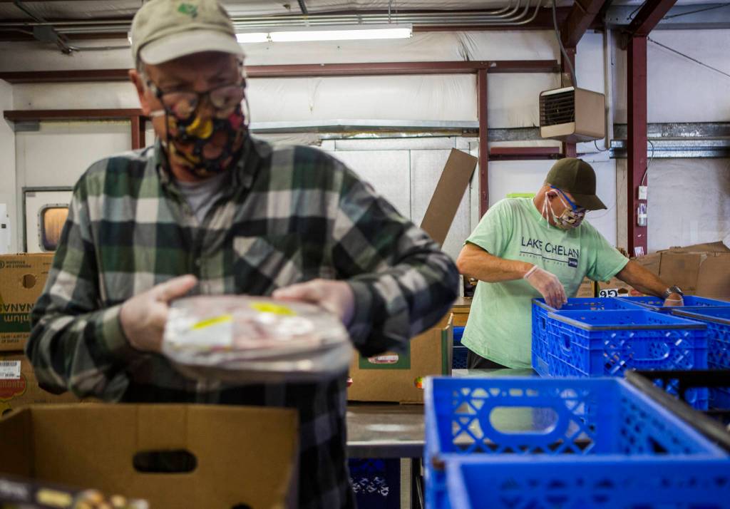 Bob Blanchard, left, and Ron Petrick sort through meat donations at the Sky Valley Food Bank on Friday, May 15, 2020 in Monroe, Wa. (Olivia Vanni / The Herald)