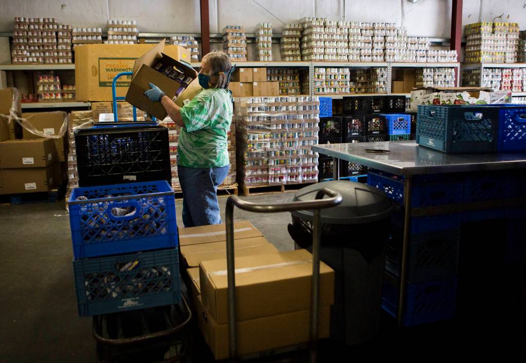 Mary Minor empties boxes of ground beef into storage containers at the Sky Valley Food Bank on Friday, May 15, 2020 in Monroe, Wa. (Olivia Vanni / The Herald)
