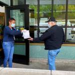 Elizabeth What-Hall, at Carl Gipson Senior Center in Everett, hands a sack lunch to Duane Conklin on Tuesday morning. (Sue Misao / The Herald)