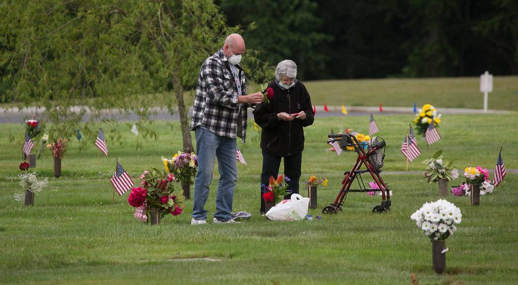 Ben Johnson helps his mother, Sadie, arrange flowers for his father, Ben, Monday at Floral Hills cemetery in Lynnwood. (Andy Bronson / The Herald)
