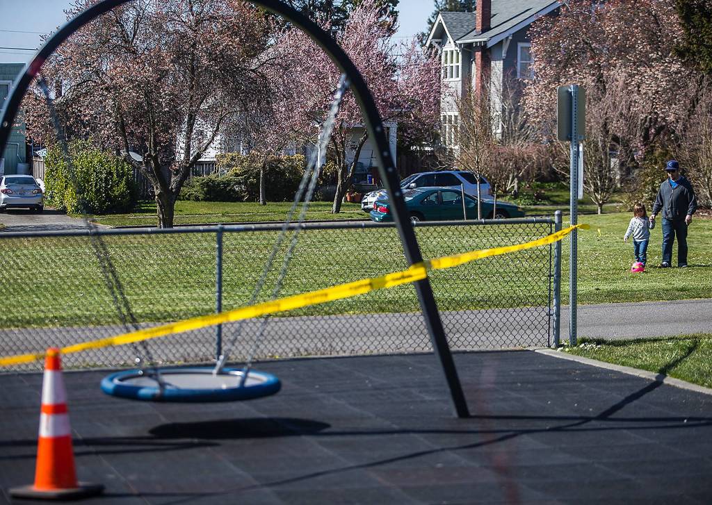 Liam Fitzgerald and his daughter, Lillian, 3, walk past a closed Northwest Everett Neighborhood Park. (Olivia Vanni / The Herald)