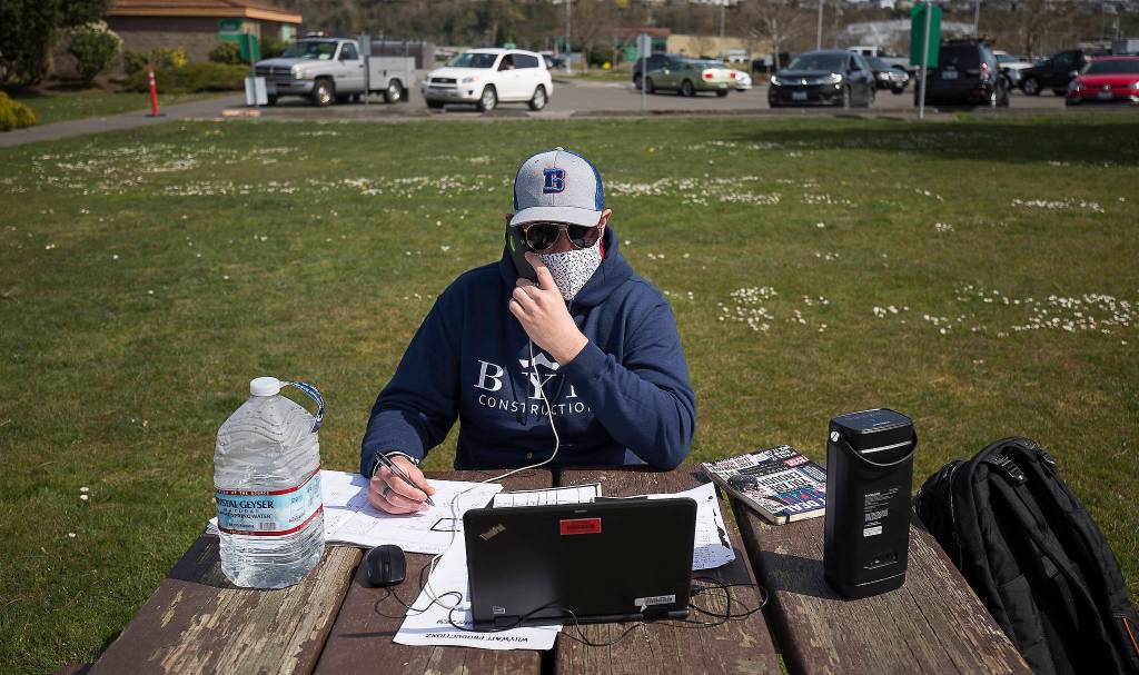 Bill Snickers chats on the phone, setting up dates of a rap tour taking place in Tennessee, while he enjoys the sun at the 10th Street Park in Everett. (Andy Bronson / The Herald)