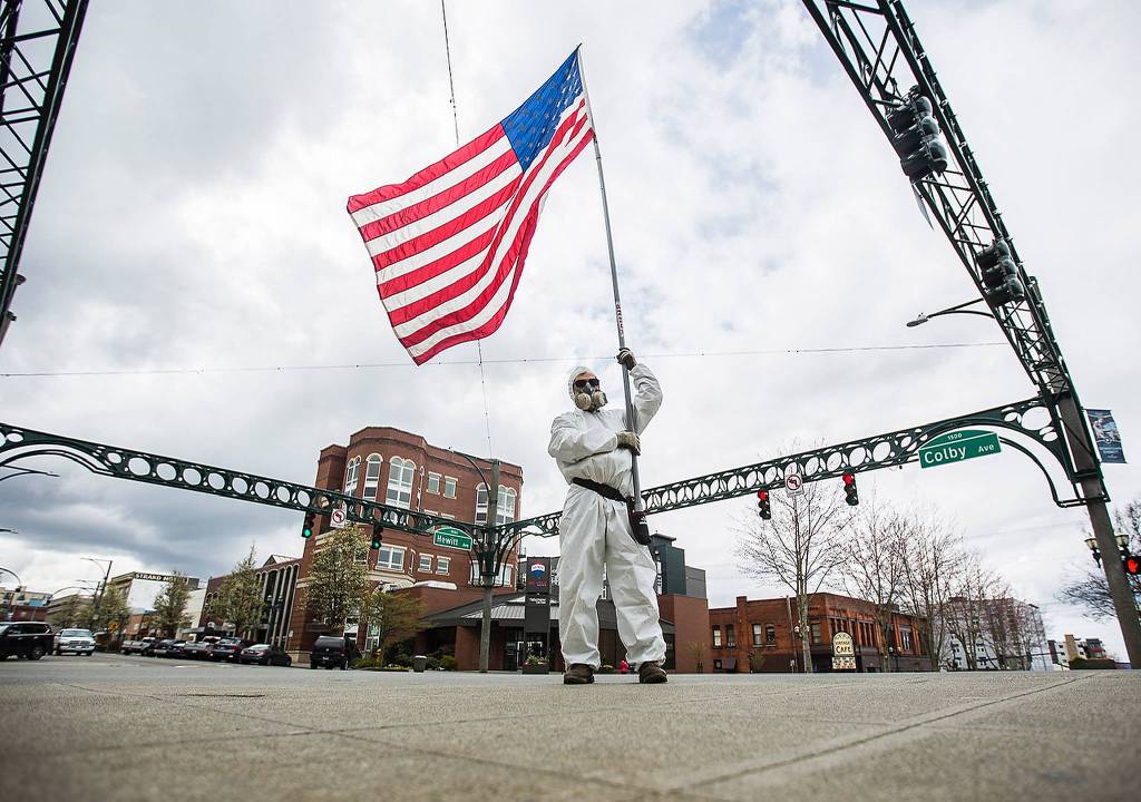 Kevin Moeller stands on the corner or Colby and Hewitt avenues in Everett, waving an American flag in support of troops. (Olivia Vanni / The Herald)