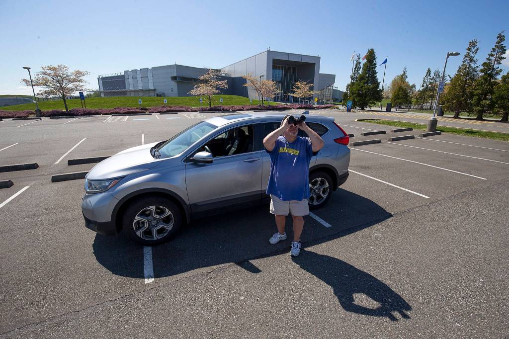 Craig Weishaar watches planes take off from Paine Field while parked in the empty Future of Flight parking lot in Mukilteo. (Andy Bronson / The Herald)