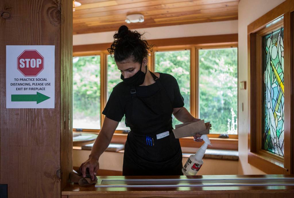 Sierra Wilkin wipes down surfaces at the Cama Beach Cafe. (Olivia Vanni / The Herald)