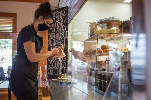 Sierra Wilkin wipes down pens for customers during the opening day of Cama Beach Cafe on Friday, May 22, 2020 in Camano Island, Wa. (Olivia Vanni / The Herald)