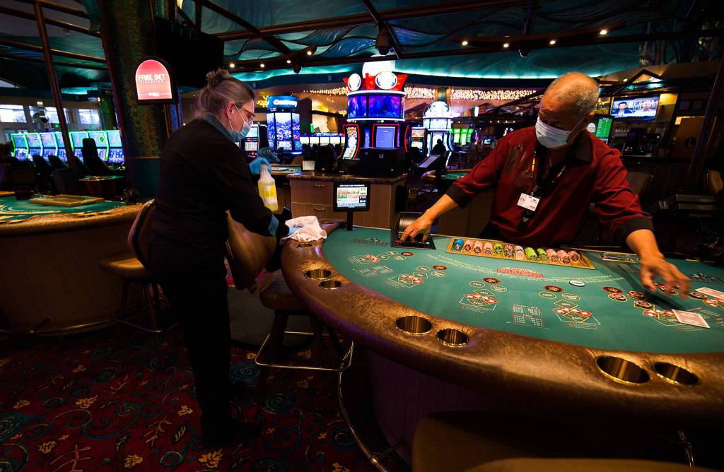 Dealer Hope Warren disinfects a table as the Tulalip Resort Casino reopens Tuesday. (Andy Bronson / The Herald)