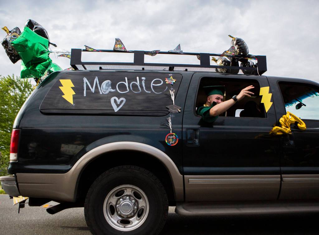 A Marysville Getchell High School graduate waves out of their car as people cheer during the Marysville-Tulalip All High School Senior Parade on Friday, May 29, 2020 in Marysville, Wa. (Olivia Vanni / The Herald)