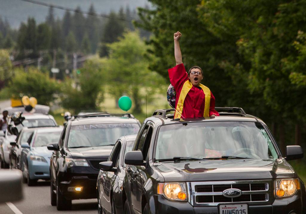 A Marysville Pilchuck High School graduate pumps their fist in the air as they drive in the Marysville Tulalip All High School Senior Parade on Friday, May 29, 2020 in Marysville, Wa. Hundreds of local high school seniors turned out to join in on the parade to celebrate their graduation and senior year in an unconventional manner due to COVID-19 restrictions. (Olivia Vanni / The Herald)