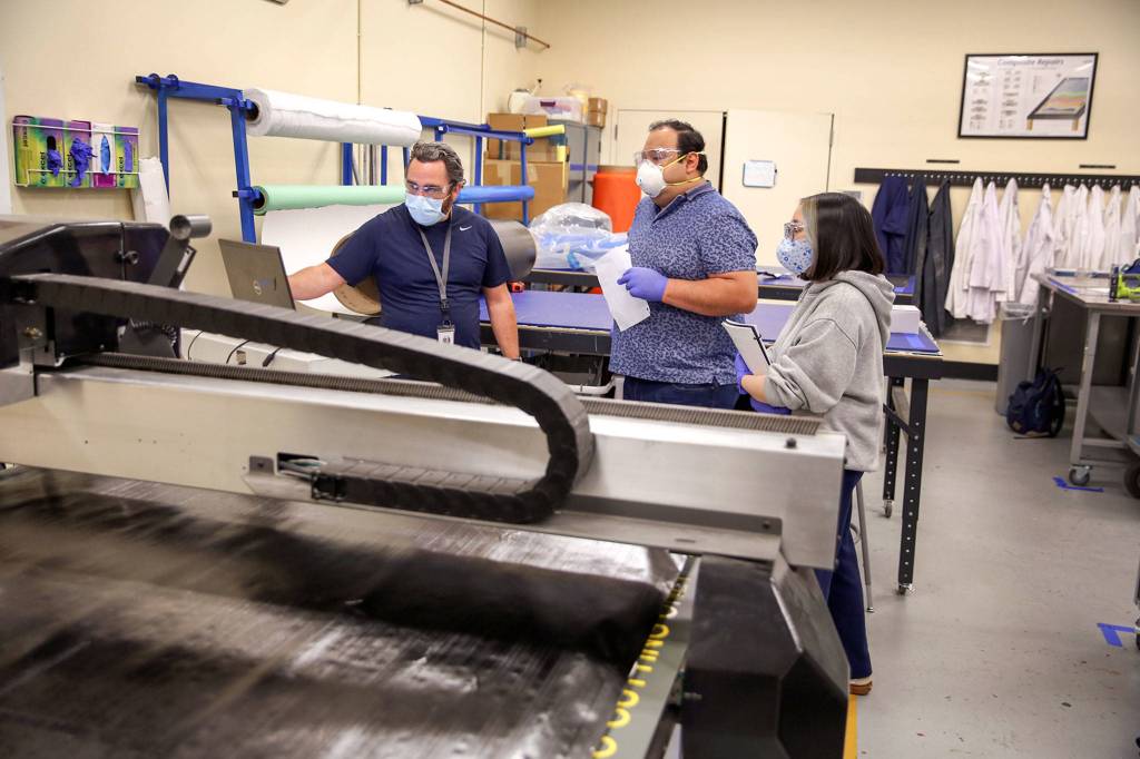 Instructor Michael Patching (left) leads students Manuel Bancalari and Vy Dinh through coursework at the Advanced Manufacturing Training & Education Center at Everett Community College. (Kevin Clark / The Herald)