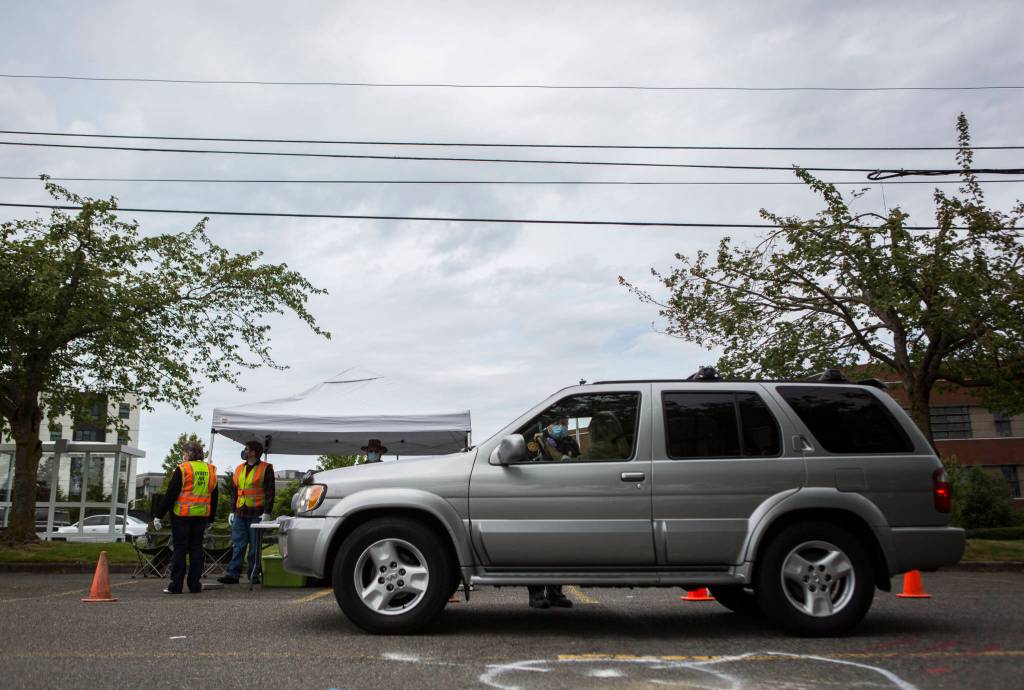 A person drives up to inquire about free face masks in Everett. (Olivia Vanni / The Herald)
