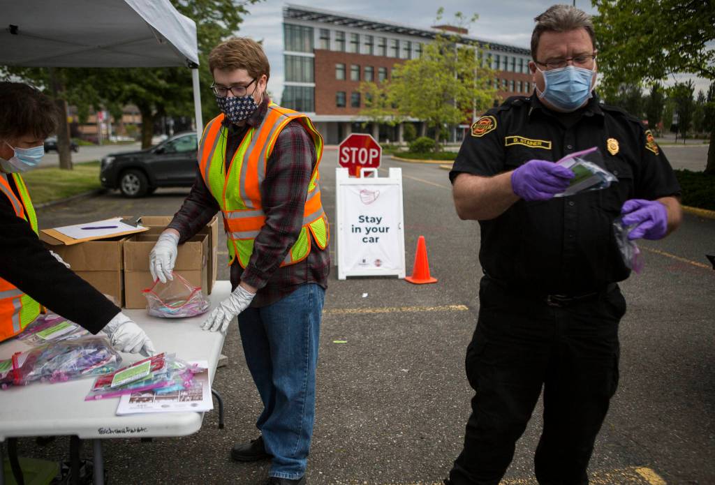 Volunteers sort and restock face masks at a recent free mask drive-thru hosted by Everett Emergency Management. (Olivia Vanni / The Herald)