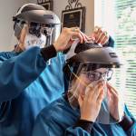 Amy Norman (left) helps Makenzi Sparks put on personal protective equipment Friday in Everett. (Kevin Clark / The Herald)