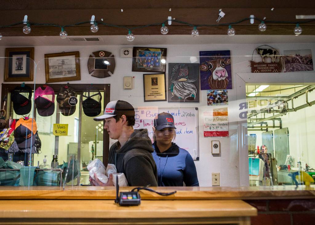 Kevin Faulkner, left, and Sarah Floe take customer orders from behind plexiglass at Silvana Meats on Friday, May 29, 2020 in Silvana, Wa. (Olivia Vanni / The Herald)