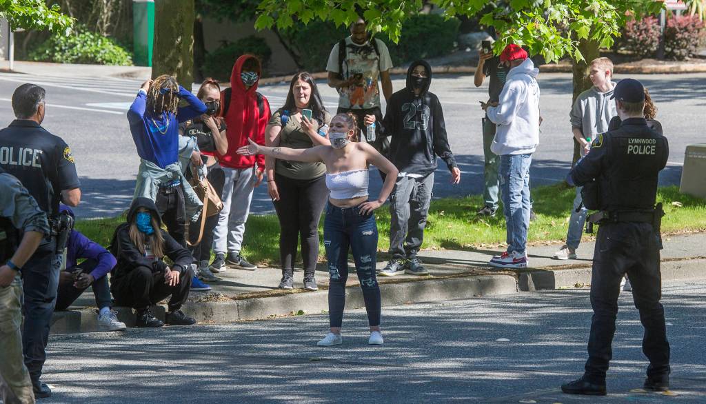 Lynnwood police listen as a young woman complains after being confronted when she and others wandered past barricades at the Alderwood mall on Monday in Lynnwood. (Andy Bronson / The Herald)