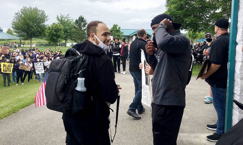 Organizer Isaiah Cole (left) greets his former high school football coach Michael Bumpus (right) at the Justice March for George Floyd in Monroe on Wednesday. (Nick Patterson / The Herald)