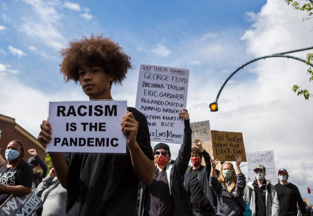 Protesters walk along Colby Avenue on Saturday in Everett. (Olivia Vanni / The Herald)
