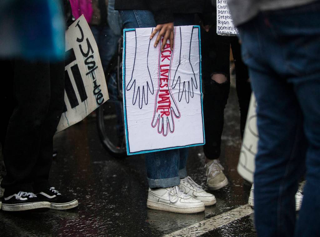 A protester holds a soaked sign in the rain during the Black Lives Matter protest on Saturday in Everett. (Olivia Vanni / The Herald)