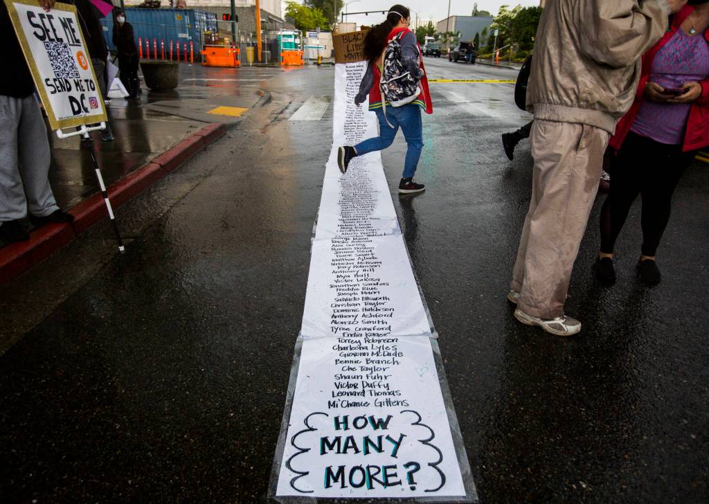 On Saturday in Everett, multiple sheets of laminated paper listed the names of black people killed by police. (Olivia Vanni / The Herald)