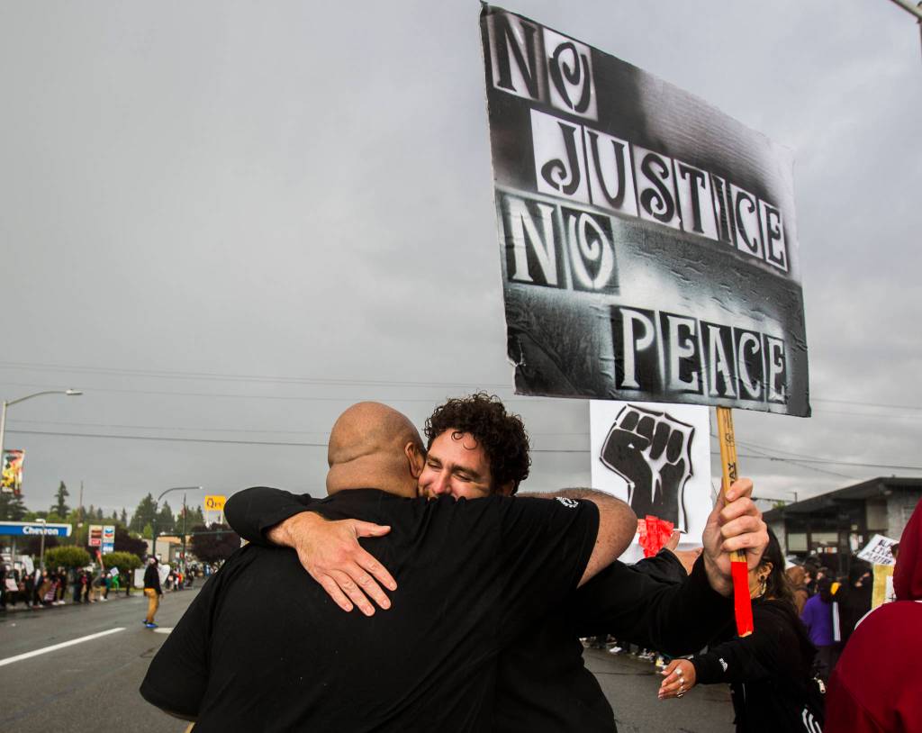 William Tuata (left) and James Bearden hug after the Black Lives Matter protest on Saturday in Everett. (Olivia Vanni / The Herald)