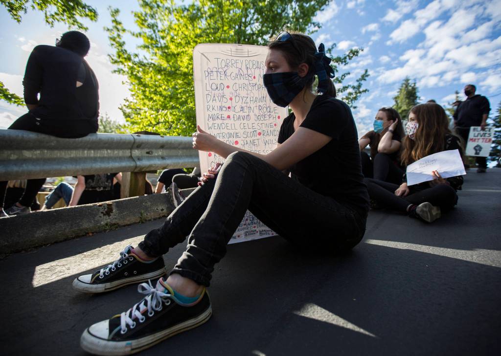 Kylara Triel uses her sign to shield herself from the sun during the Black Lives Matter protest on Sunday in Mukilteo. (Olivia Vanni / The Herald)