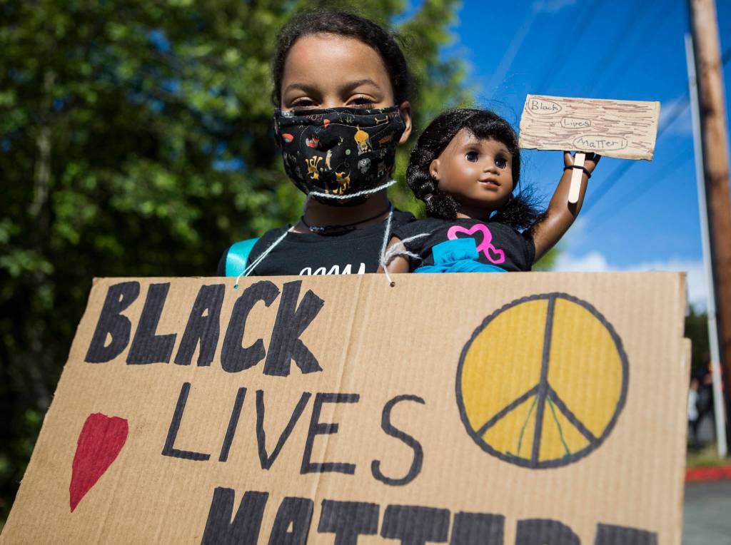 Olivia Brown, 8, holds her doll Melody who is also holding a Black Lives Matter sign during the Black Lives Matter protest on Sunday in Mukilteo. (Olivia Vanni / The Herald)