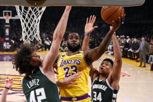 Los Angeles Lakers forward LeBron James, center, shoots as Milwaukee Bucks center Robin Lopez, left, and forward Giannis Antetokounmpo defend during the first half of an NBA basketball game on March 6 in Los Angeles. (AP Photo/Mark J. Terrill)
