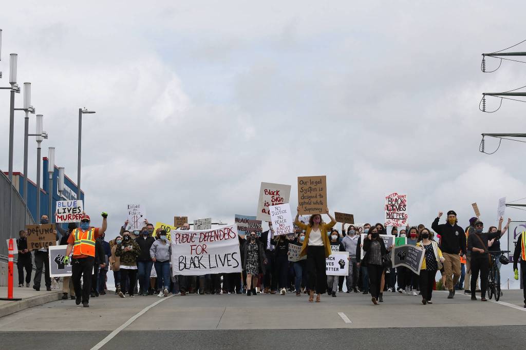 The Snohomish County Public Defender Association and their supporters march Monday afternoon on Broadway in Everett. (Andy Bronson / The Herald)