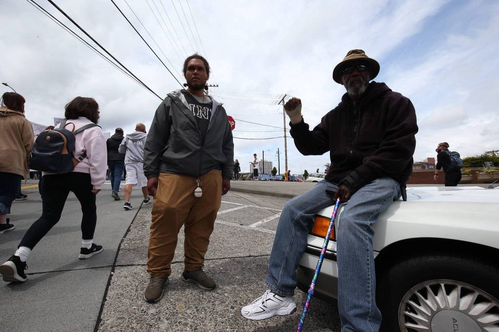 Michael Reames holds up a fist as he watches protesters march through north Everett on Monday. (Andy Bronson / The Herald)