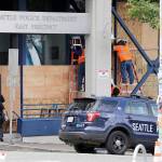 Workers put up plywood over the windows of a Seattle police precinct Monday in Seattle, where protests continued the night before over the death of George Floyd, a black man who was in police custody in Minneapolis. (AP Photo/Elaine Thompson)