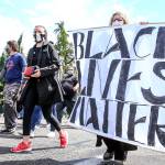 Protesters hold a large banner as they march through Marysville Thursday, in an effort to speak out against racism. (Kevin Clark / The Herald)