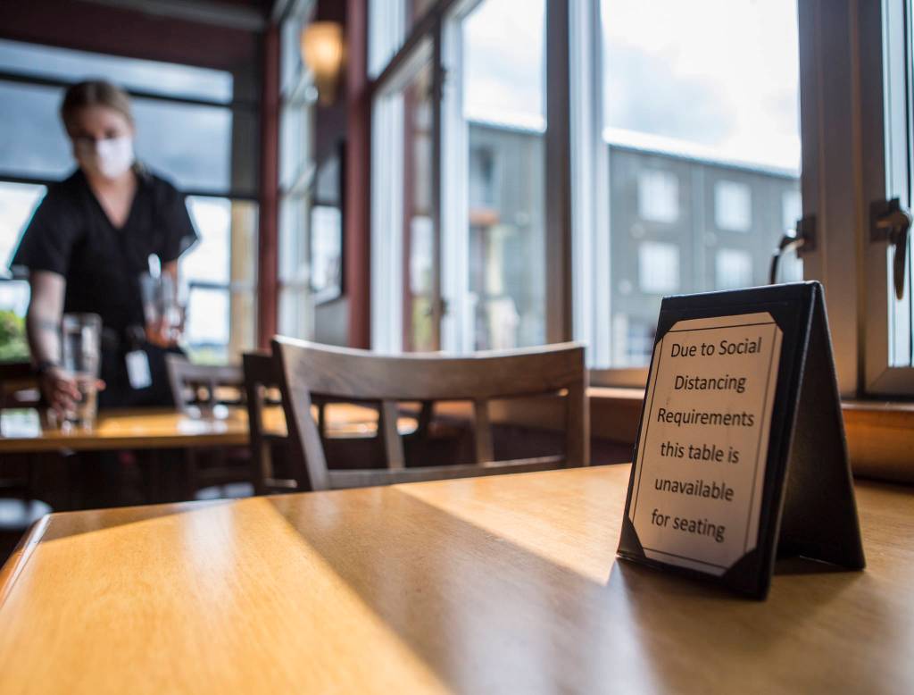 An empty table has a sign alerting customers to social distancing guidelines at Lombardis Italian Restaurant on Saturday in Everett. (Olivia Vanni / The Herald)