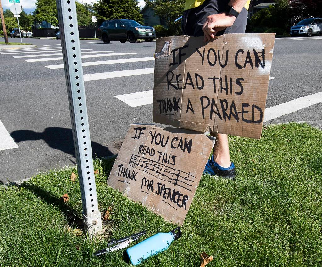 A mans holds signs in thanks Wednesday for music teacher George Spencer and the staff of Whittier Elementary in Everett. (Andy Bronson / The Herald)