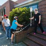 Leslie Bringedahl and her husband, Mark, take a bag of books from circulation manager Carol Ellison during curbside pick-up at the Everett Public Library on Wednesday. (Andy Bronson / The Herald)