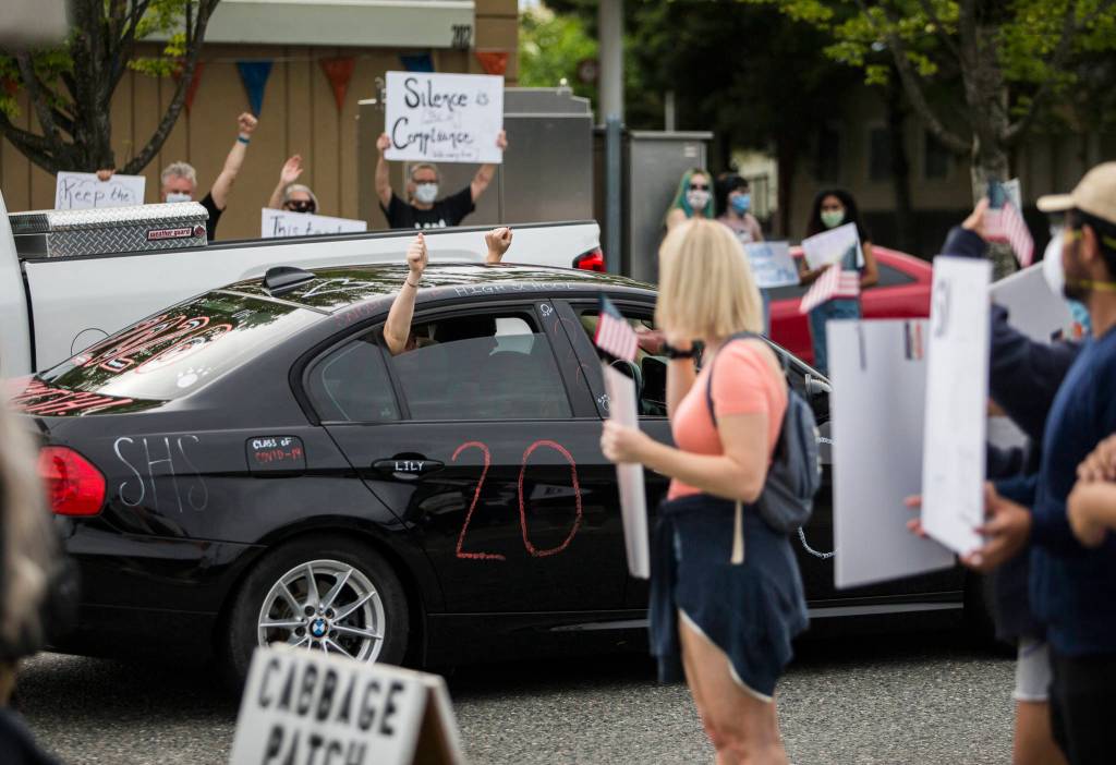 A car drives by protesters with passengers holding their fists out of the windows in support on Friday, June 19, 2020 in Snohomish, Wa. (Olivia Vanni / The Herald)