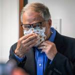 In this file photo, Washington Gov. Jay Inslee puts on his face mask after speaking to the media, Wednesday, May 20, 2020, in Tumwater, Wash. (Steve Ringman/The Seattle Times via AP, Pool)